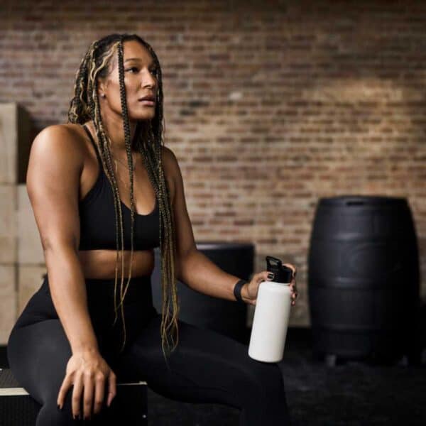 woman resting after workout next to ice barrel 400 in a gym