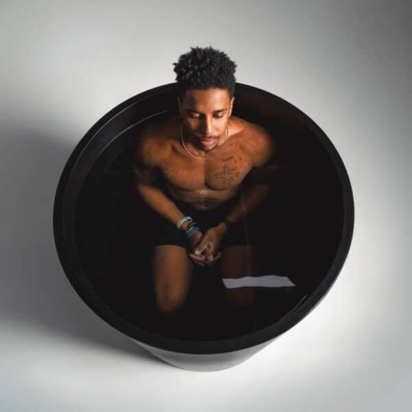 Man sitting contemplatively in a dark round tub.