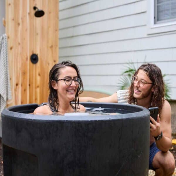 Man and woman doing cold plunge in ice barrell 300