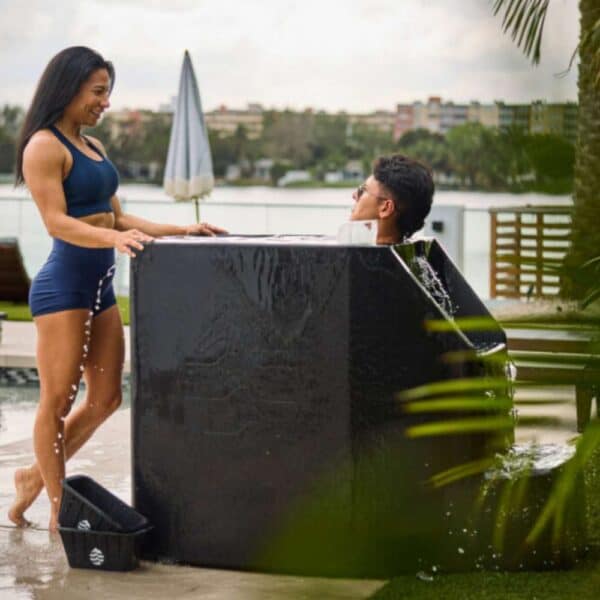 man in Ice barrel 500 plunge tub with woman watching